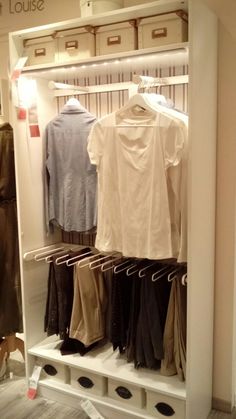 an open closet with clothes on hangers and pants hanging from the racks in front