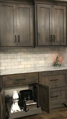 a kitchen with dark wood cabinets and white counter tops, an open drawer under the sink