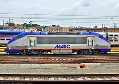 two blue and silver trains on tracks next to each other with power lines in the background