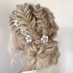 a woman with blonde hair wearing a braided updo and flowers in her hair