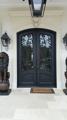 the front entrance to a home with two lions on either side and an iron door