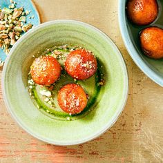 two bowls filled with food on top of a wooden table next to another bowl full of food