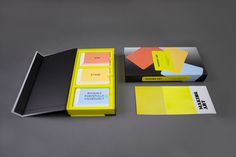 an assortment of business cards and stationery on a gray surface, including a yellow folder