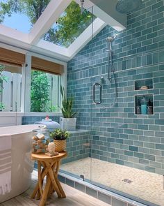 a bath room with a stand up shower next to a sink and a tub under a skylight