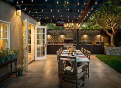 an outdoor dining area is lit up at night with string lights strung from the ceiling