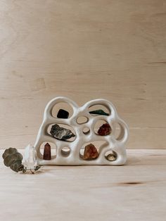 a small white sculpture with rocks and stones in it's center on a wooden surface