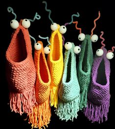 several knitted purses are lined up in different colors and sizes with balls on them