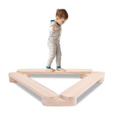 a small child is standing on a wooden balance beam with one foot in the air