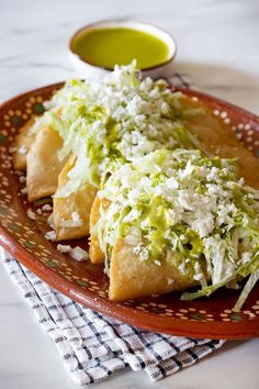 some food is sitting on a red plate with green sauce in the bowl next to it