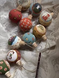 an assortment of painted wooden ornaments on a lace tablecloth with a crochet hook