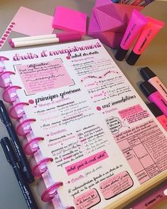 a pink notebook with writing on it next to markers and pens