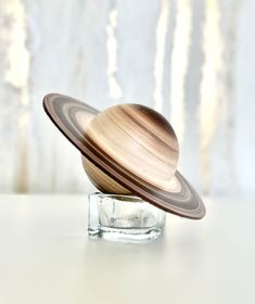 a wooden object sitting on top of a glass block in front of a white wall