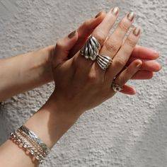 two hands are holding each other with rings on their fingers and bracelets around them