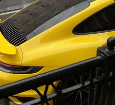 a yellow sports car parked next to a fence