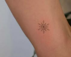 a small snowflake tattoo on the right side of the arm is shown in black ink