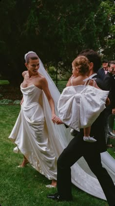 a woman in a wedding dress walking down the aisle with a man holding her hand