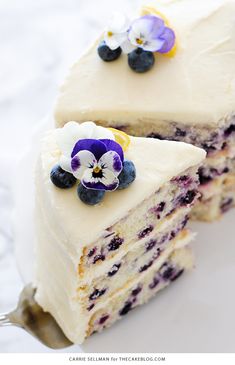 a piece of cake with white frosting and blueberries