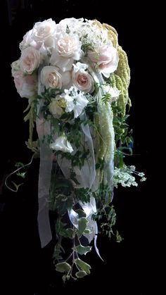 a bouquet of white flowers and greenery on a black background