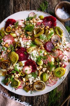 a salad with radishes, cucumbers and nuts on a white plate