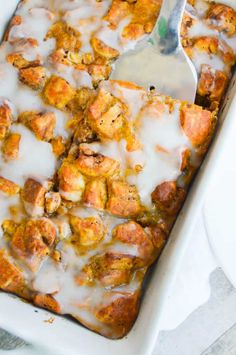 a casserole dish filled with meat and cheese covered in icing next to a white plate