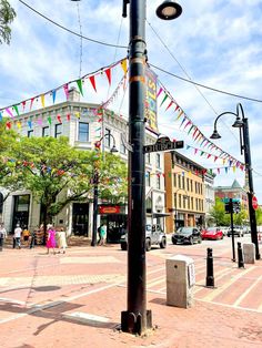 a street light on the side of a road with flags hanging from it's poles