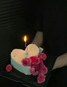 a heart - shaped cake with roses on it and a single candle in the middle