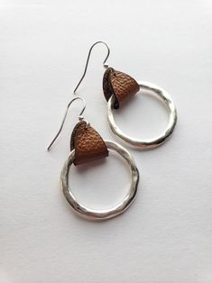 pair of silver and brown leather earrings on white background