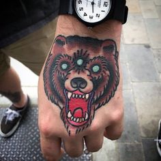 a hand with a bear tattoo on it's wrist and a clock in the background