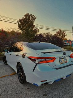 the rear end of a white car parked in a parking lot