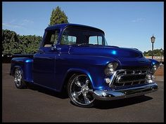 an old blue truck parked in a parking lot