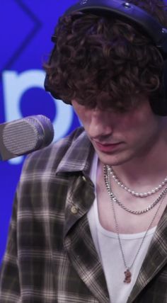 a young man wearing headphones while standing in front of a blue screen and microphone