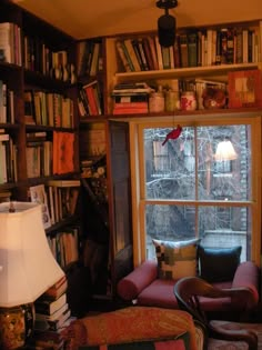 a living room filled with lots of furniture and bookshelves next to a window