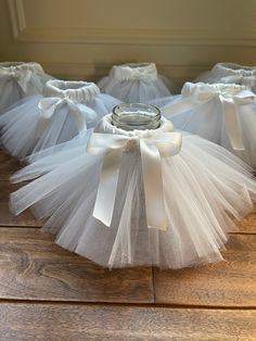 several white tulle skirts with a glass jar in the center on a wooden floor