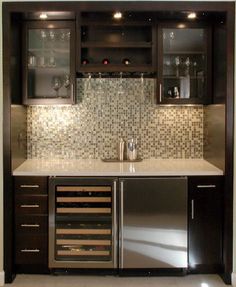 a kitchen with black cabinets and stainless steel appliances in the center, along with wine glasses on the shelves