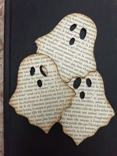 two book pages that have been cut into shape to look like ghost faces