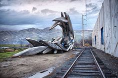 a train track that is next to a building and some mountains in the back ground