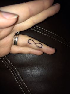 a woman's hand with a ring on her finger and an infinite sign tattoo