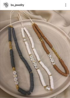 three different necklaces on a white plate with gold beaded beads and black cord