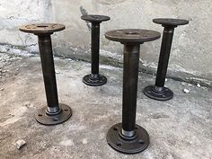 three black metal pedestals sitting next to each other on the cement floor in front of a stone wall