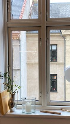 a window sill with candles, books and other items on it in front of the window