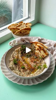 a bowl filled with food sitting on top of a table next to a plate of bread