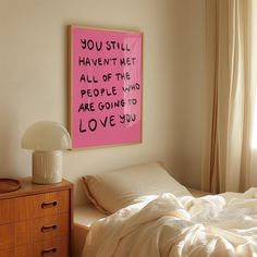 a bed with white sheets and a pink sign on the wall above it that says you still have to meet all of the people who are going to love you