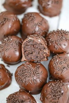 chocolate candies with frosting and sprinkles on a white surface, ready to be eaten