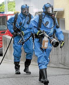 two people in blue diving suits walking down the street with water bottles on their feet