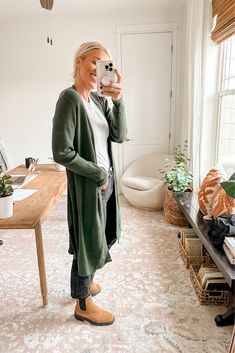 a woman taking a selfie in her living room while holding a coffee cup and looking at the camera