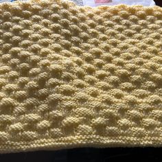 a yellow crocheted blanket sitting on top of a table next to a pair of scissors