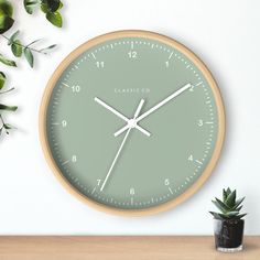 a clock on the wall next to a potted plant