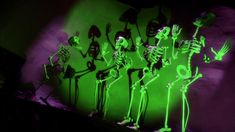 a group of skeletons standing next to each other in front of a green wall with neon lights