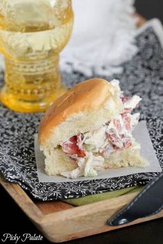 a sandwich with meat and cheese on a plate next to a glass of wine in the background