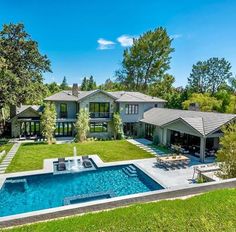 an aerial view of a house with a swimming pool in the foreground and lush green yard